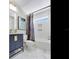 Bright bathroom features a blue vanity, marble floors, shower and tub with white tile at 4702 W Heron Ln, Tampa, FL 33629