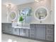 Bright bathroom featuring double vanity, round mirrors, and a large window for plenty of natural light at 4702 W Heron Ln, Tampa, FL 33629