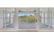 Enclosed patio featuring gray wood-look flooring, ceiling fans, and a view of a serene pond with lush greenery at 4702 W Heron Ln, Tampa, FL 33629