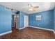 Bedroom features blue walls, hardwood floors, a ceiling fan, and an open doorway at 5051 Bonito Dr, New Port Richey, FL 34652
