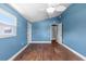 Empty bedroom features blue walls, hardwood floors, a ceiling fan, and natural light at 5051 Bonito Dr, New Port Richey, FL 34652