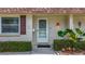 Close-up of the home's front entrance with storm door, brick facade, and manicured shrubbery at 602 Mindy Dr, Largo, FL 33771