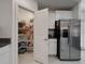 A well-stocked pantry with wire shelving sits adjacent to stainless steel refrigerator in this kitchen at 6444 Bar S Bar Trl, Zephyrhills, FL 33541