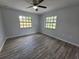 A bright bedroom featuring wood floors, two windows, and a ceiling fan at 7278 Radcliff St, Spring Hill, FL 34606