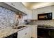 Well-lit kitchen with white cabinets, stainless steel appliances, granite countertops and stylish tile backsplash at 7465 Bay Island S Dr # 213, South Pasadena, FL 33707