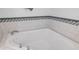 Close-up of white corner bathtub featuring decorative tiling at 8203 Kirkwood Dr, Tampa, FL 33634