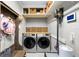 Well-organized laundry room with front loading machines, storage, and gray walls at 8203 Kirkwood Dr, Tampa, FL 33634