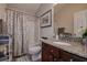 Well-lit bathroom features a granite-topped vanity and shower with geometric patterned curtain at 8447 Shallow Creek Ct, New Port Richey, FL 34653