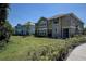 Manicured lawn with sidewalk leading to townhomes painted in neutral and blue colors at 8447 Shallow Creek Ct, New Port Richey, FL 34653