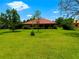 Large backyard featuring green grass and a house with a red tile roof, perfect for outdoor activities at 9313 Lisbon St, Seffner, FL 33584