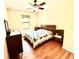 Bright bedroom with wood floors, ceiling fan, and a comfortable bed with decorative patchwork quilt at 9313 Lisbon St, Seffner, FL 33584