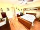 Bright bedroom featuring wood floors, ceiling fan, shelf and a white and floral patterned bedspread at 9313 Lisbon St, Seffner, FL 33584