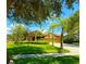 Charming single-story home with lush landscaping, a manicured lawn, and a long driveway leading to a three-car garage at 9313 Lisbon St, Seffner, FL 33584