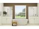 Spa-like bathroom features a soaking tub, separate vanities, and a large window with a peaceful outdoor view at 9376 Gladsome Dr, Land O Lakes, FL 34637