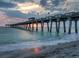 A serene scene of a pier stretching into the ocean as the sun sets, casting a warm glow at 984 Chickadee Dr, Venice, FL 34285