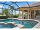 Screened-in pool and spa with travertine patio and outdoor kitchen overlooking the golf course at 984 Chickadee Dr, Venice, FL 34285