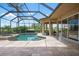 Screened-in pool and spa with travertine patio and outdoor kitchen at 984 Chickadee Dr, Venice, FL 34285