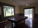 Light-filled living room featuring a pool table and access to the screened lanai and backyard at 9127 Woodridge Run Dr, Tampa, FL 33647