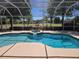 Covered pool area featuring a hot tub with views of a manicured backyard and distant greenery at 9127 Woodridge Run Dr, Tampa, FL 33647
