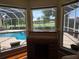 A quaint writing desk sits in front of bay windows with a serene pool and golf course view at 9127 Woodridge Run Dr, Tampa, FL 33647