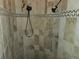 Detailed look at the walk-in shower featuring decorative stone tiles and built in niche at 9127 Woodridge Run Dr, Tampa, FL 33647