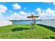 Grassy backyard with lake view, white fence and outdoor table with umbrella at 1015 7Th Nw Ave, Ruskin, FL 33570