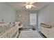 Bright Bedroom with ceiling fan, cloud rug, white crib, and comfortable rocking chair at 10449 Hunters Haven Blvd, Riverview, FL 33578