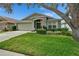Landscaped front yard of single-story home featuring green grass, shrubbery, and an attached garage at 10449 Hunters Haven Blvd, Riverview, FL 33578