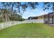 A green backyard with a white vinyl fence and a view of the screened-in patio and the home's exterior at 11121 Running Pine Dr, Riverview, FL 33569