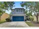 This two-story home has a blue garage door, a yellow front door, mature trees and landscaping at 11121 Running Pine Dr, Riverview, FL 33569