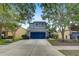 A two-story home with a blue garage door is framed by trees in this attractive shot at 11121 Running Pine Dr, Riverview, FL 33569