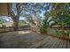 A spacious wooden deck overlooking a landscaped yard with mature trees, offering a serene outdoor living space at 1142 Lancer Ln, Tarpon Springs, FL 34689