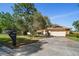 Charming one-story home with a well-maintained lawn, mature trees, and a driveway leading to an attached two-car garage at 1142 Lancer Ln, Tarpon Springs, FL 34689