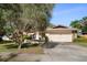 Charming single-story home featuring a well-manicured lawn and a spacious driveway leading to an attached two-car garage at 1142 Lancer Ln, Tarpon Springs, FL 34689