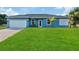 Charming single-story home featuring a well-manicured lawn, blue exterior, and a two-car garage at 11635 Willmington Blvd, Port Charlotte, FL 33981