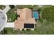 An aerial view of a home with a brown tile roof, screened pool, mature landscaping, and driveway at 1201 Peridot Ln, Sun City Center, FL 33573