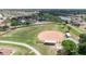 Aerial view of a lush baseball field near a community with a lake and surrounding houses at 1201 Peridot Ln, Sun City Center, FL 33573