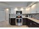 Kitchen featuring white upper cabinets, dark lower cabinets, and stainless steel appliances at 1201 Peridot Ln, Sun City Center, FL 33573
