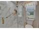 Bathroom boasts a walk-in shower, marble walls, and gold fixtures, providing luxury and elegance at 1201 Peridot Ln, Sun City Center, FL 33573