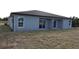 Home exterior with sliding glass doors to small back porch and unlandscaped backyard at 12223 Kirk Ave, Port Charlotte, FL 33981