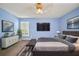 Relaxing blue bedroom featuring a mounted TV, sleek furnishings, and a cozy bed at 1226 Baycrest Dr, Wesley Chapel, FL 33543