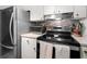 Kitchen with stainless steel appliances, white cabinets, and mosaic backsplash at 12760 Indian Rocks Rd # 410, Largo, FL 33774