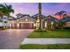 Charming home with a brick driveway, three-car garage, lush landscaping, and elegant stone and stucco facade at 1416 Via Verdi Dr, Palm Harbor, FL 34683