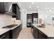 Well-appointed kitchen featuring dark cabinetry, stainless steel appliances, and an island with a sink at 1416 Via Verdi Dr, Palm Harbor, FL 34683