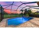Screened-in in-ground pool with spa and serene golf course views during sunset at 1416 Via Verdi Dr, Palm Harbor, FL 34683