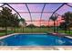 Screened-in in-ground pool with spa and serene golf course views during sunset at 1416 Via Verdi Dr, Palm Harbor, FL 34683