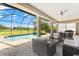 Screened-in patio featuring comfortable wicker seating with serene views of pool and golf course at 1416 Via Verdi Dr, Palm Harbor, FL 34683