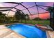 Screened-in in-ground pool with spa and serene golf course views during sunset at 1416 Via Verdi Dr, Palm Harbor, FL 34683