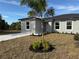 Charming single Gathering home featuring a well-manicured lawn and a shared yard with young palm tree at 17099 Carleen Ave, Port Charlotte, FL 33948