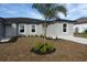 Charming single Gathering home featuring a well-manicured lawn and a shared yard with young palm tree at 17099 Carleen Ave, Port Charlotte, FL 33948